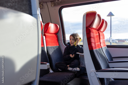 Cute little girl talking by telephone  in train 