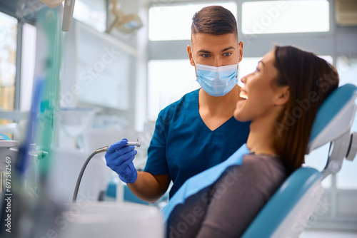 Male dentist during examining teeth of young woman at dental clinic.