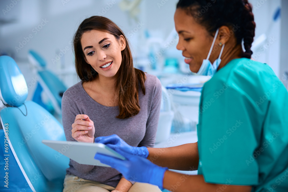 Obraz premium Smiling woman and her dentist using digital tablet during appointment at dental clinic.