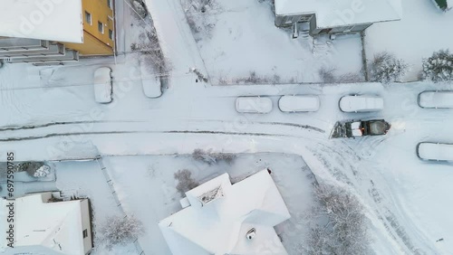 Aerial drone top view of snow plow salt spreader machine cleaning the street in urban aria in the winter season photo