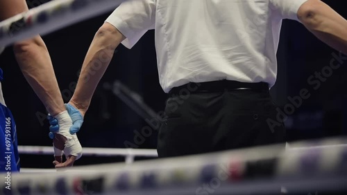 The judge raises his hand to a man in the boxing ring. Referee declaring a winner of a fight
