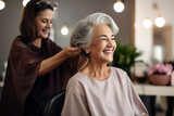 A hairdresser styles the hair of an elderly gray-haired woman.