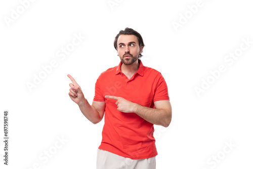 young 35 year old european man with a styled haircut and beard dressed in a red t-shirt points his hand to the side on a white background with copy space © Ivan Traimak