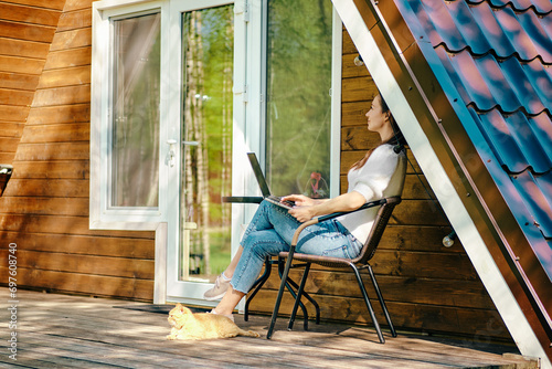 Digital nomad with laptop on veranda of tiny house photo