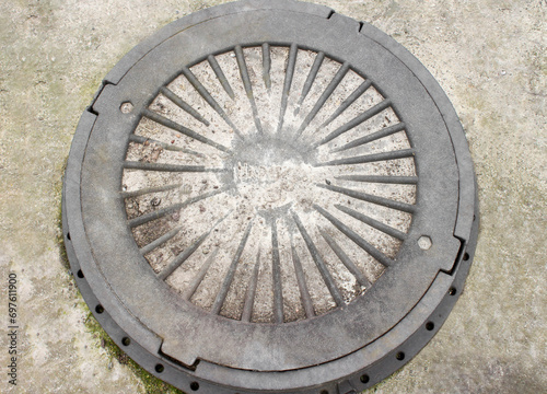 Manhole cover close up picture. Close-up of old metal sewer manhole on a concrete base