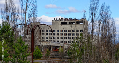 A dilapidated building with broken windows surrounded by overgrown trees. photo