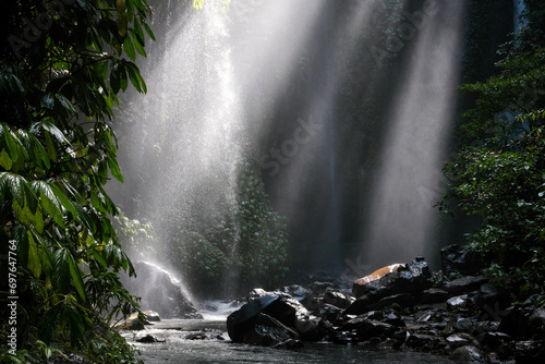 Sun beams in a reain forest nearby Hidden waterfall Sekumpul. Bali, Indonesia. photo