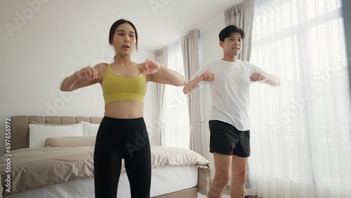 Young couple in sportswear are doing exercises together at home on morning. Enjoying cardio activity. 