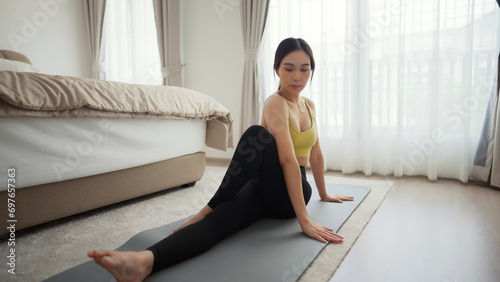 Asian young woman performing a stretching yoga exercise at home on sunny morning. Concept of healthy lifestyle and fitness.