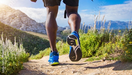 men s legs with sports shoes and a backpack run along a mountain path