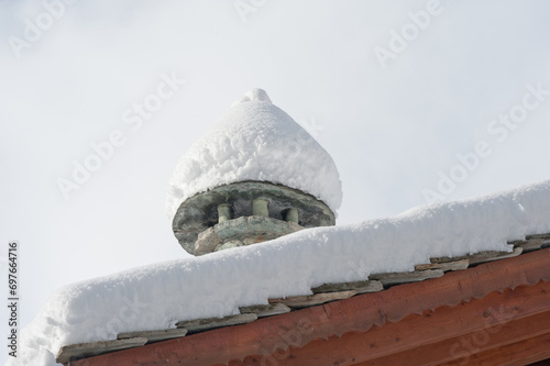 Tetto dello chalet in montagna con la neve sul comignolo photo