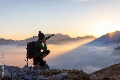 Woman Tourist talking on her Phone From Remote Locations in High Mountains And With Her Hand Showing a Point in the Distance