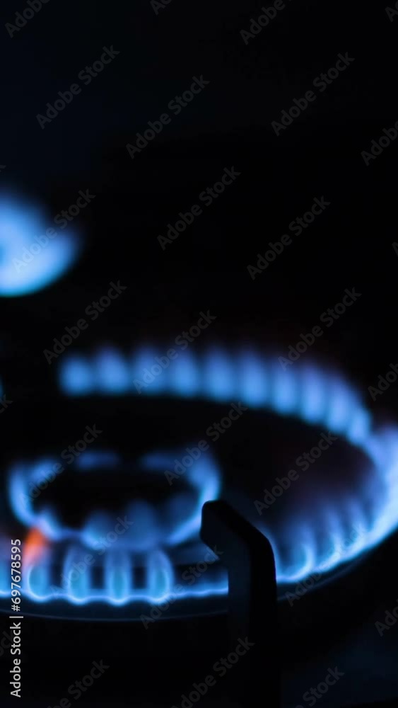 Lighting a fire on a kitchen gas stove. A close-up of the burning flame of the burner. Vertical video