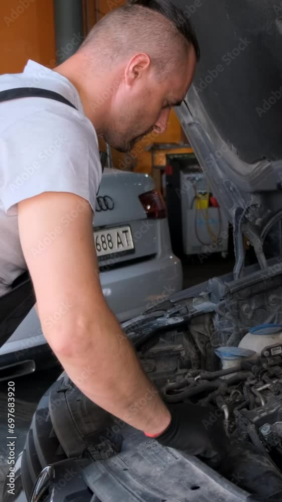 Mechanic working on car engine in garage workshop, concept of car service and car maintenance. Vertical video Mechanic working on car engine in garage workshop, concept of car service and car maintenance. Vertical video