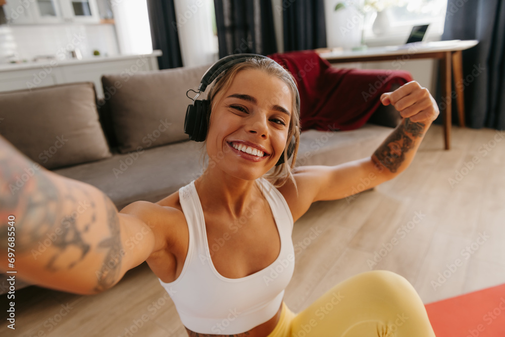 Top view of happy sporty woman making selfie while resting on exercise mat after home workout Top view of happy sporty woman making selfie while resting on exercise mat after home workout