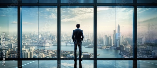 Businessman looking at the city through office window photo