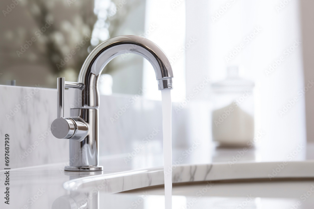 Modern white marble sink and faucet with flowing water, bright bathroom interior Modern white marble sink and faucet with flowing water, bright bathroom interior