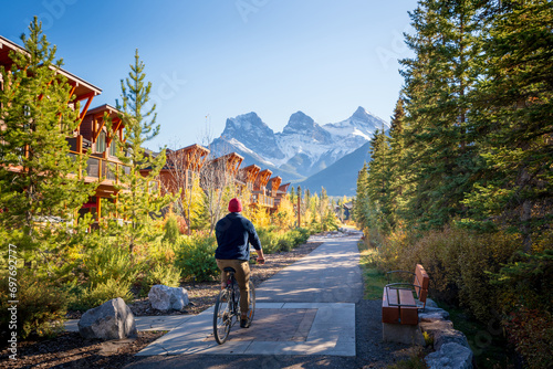 People riding a bicycle on trail in residential area. Town of Canmore street view in fall season. Alberta, Canada.
