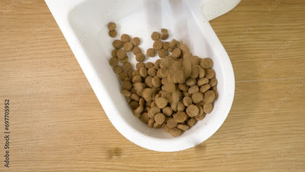 Pet food. Pouring a portion of dry food for domestic animal into white bowl Pet food. Pouring a portion of dry food for domestic animal into white bowl