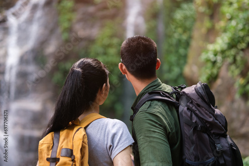 Affectionate young couple admiring a beautiful waterfall. Travel lifestyle concept. © wattana