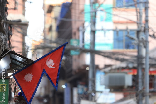 The Nepal flag proudly stands against the backdrop of the bustling streets of Kathmandu.