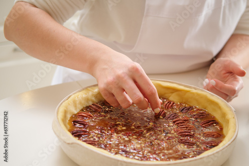 Obraz na plátně Close-up of female hands making pecan pie in the kitchen