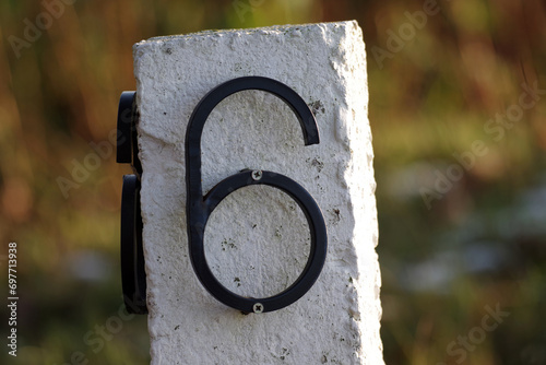 Die Zahl Sechs ist an einem weißen Stein mit Schrauben befestigt