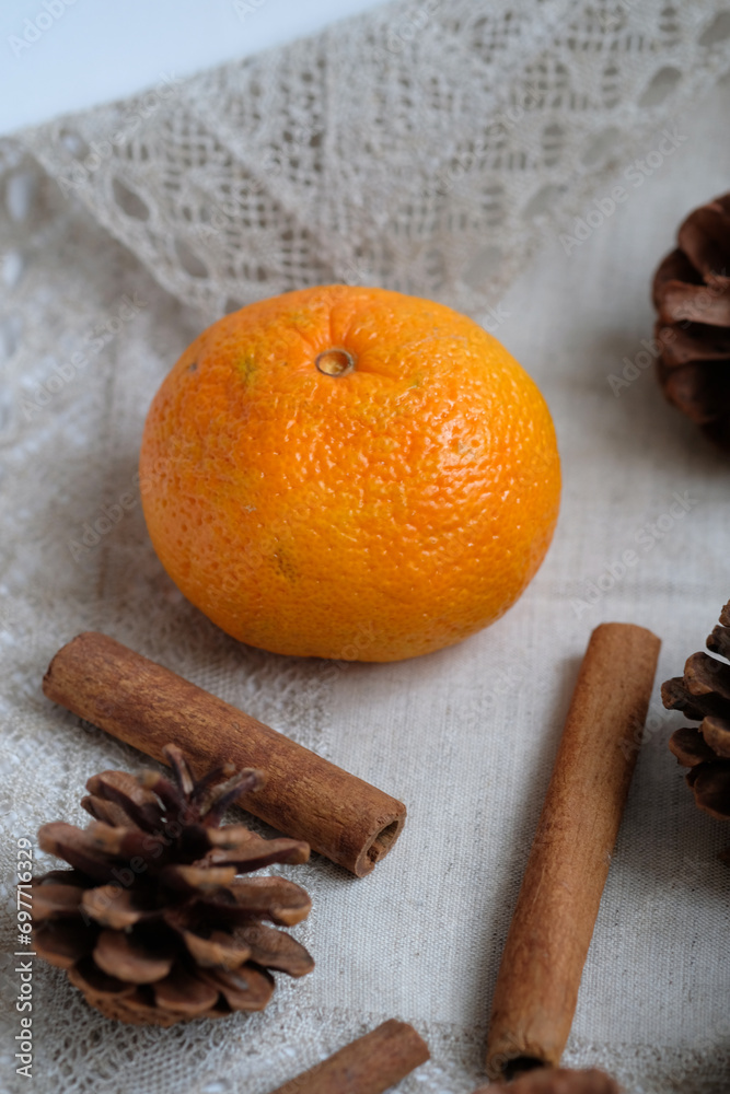 tangerine, cinnamon sticks and pine cones on a napkin tangerine, cinnamon sticks and pine cones on a napkin
