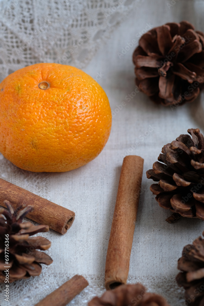 tangerine, cinnamon sticks and pine cones on a napkin