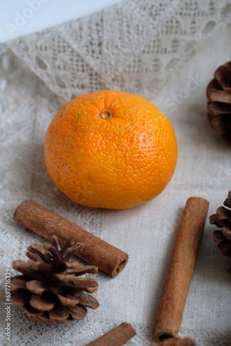 tangerine  cinnamon sticks and pine cones on a napkin