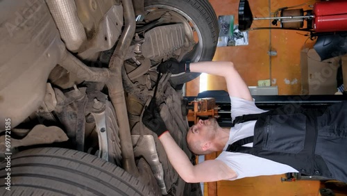 Vertical video, changing oil in a car. Auto mechanic while working in a car service. Vertical video photo