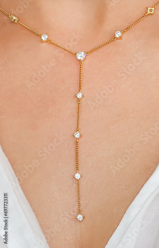 Young woman wearing a golden lariat necklace.
