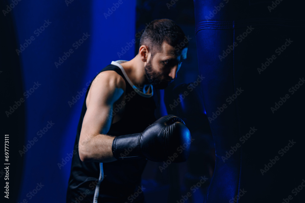 Concept banner sport boxing. Man boxer trains punches on punching bag, dark background