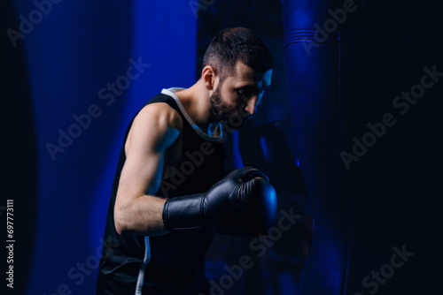 Concept banner sport boxing. Man boxer trains punches on punching bag, dark background © Parilov