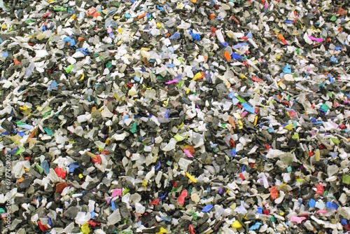 Close-up of shredded plastic pieces prepare for recycling. Raw cables material for reproduction. Sorting garbage on waste plant. Pile of scrap bottles on trash storage factory. Environmental concept