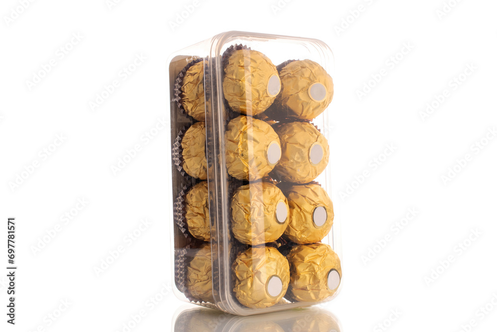 Several chocolate candies with nuts in a paper wrapper in a plastic box, macro, isolated on a white background. Several chocolate candies with nuts in a paper wrapper in a plastic box, macro, isolated on a white background.