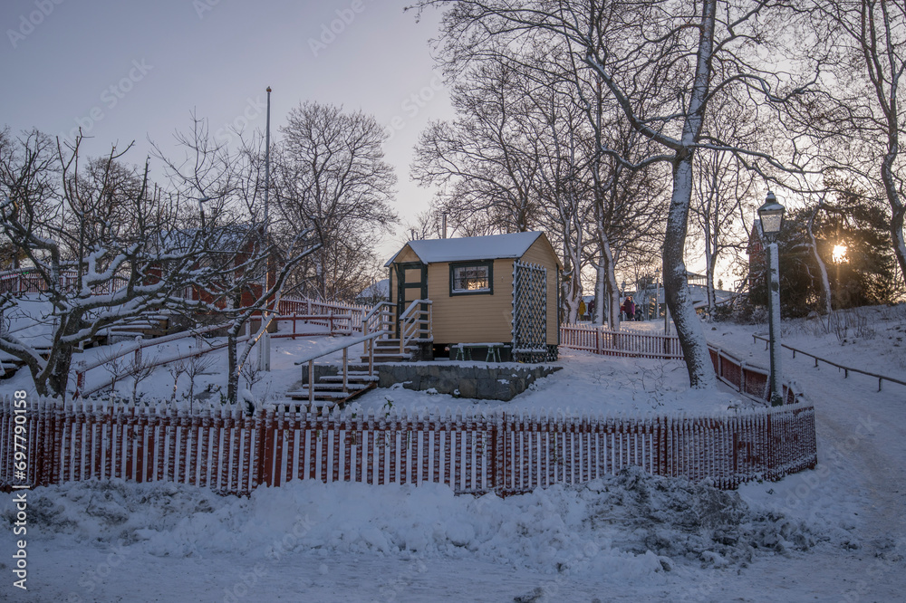 Weak winter back light, allotment house in the shadow, picked fence a snowy sunny winter day in Stockholm Weak winter back light, allotment house in the shadow, picked fence a snowy sunny winter day in Stockholm