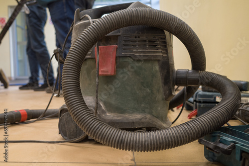 An industrial vacuum cleaner on a dusty floor in a building under construction and renovation.