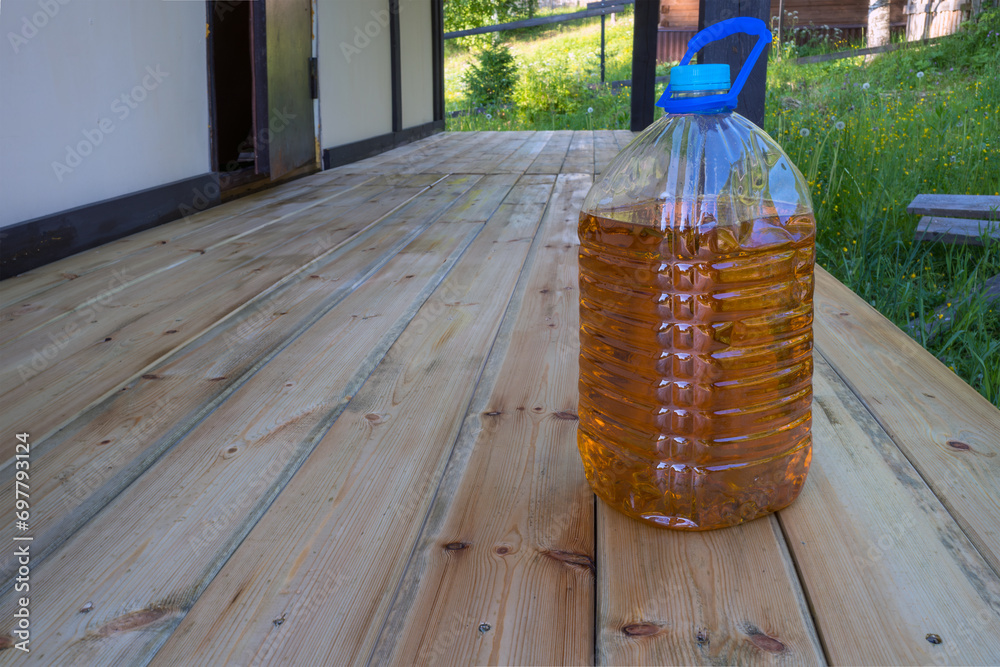 impregnation for wooden floors of the outdoor veranda with plastic container on the background of boards. a special solution for wood protection.