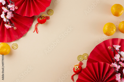 Embrace the grandeur of Chinese New Year. Top view flat lay of red paper fans, tangerines, gold coins, decorative essentials, sakura bloom on beige background with advert panel photo