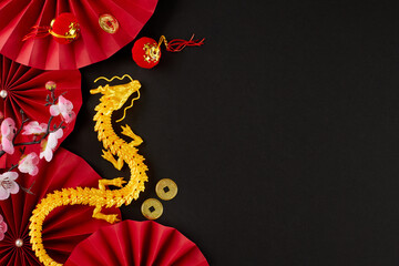 Wishing a joyful Chinese New Year 2024. Top view photo of gold dragon, paper fans, lucky coins, decorative elements, sakura on black background with advert space