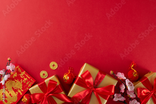 Gifting ideas to celebrate Chinese New Year. Top view photo of red New Year money red packet, gift boxes, sakura bloom, lucky coins on red background with promo area