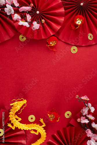 Decorating for Chinese New Year concept. Top view vertical photo of gold dragon, paper fans, lucky coins, decorative elements, sakura on red background with advert space