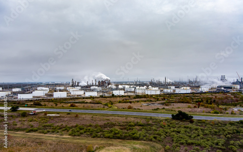 Aerial view of a Fuel Refinery in Port Arthur Texas, located on the Gulf Coast,  with fuel storage, pipelines, steam rising from tall chimneys and an overcast sky above.