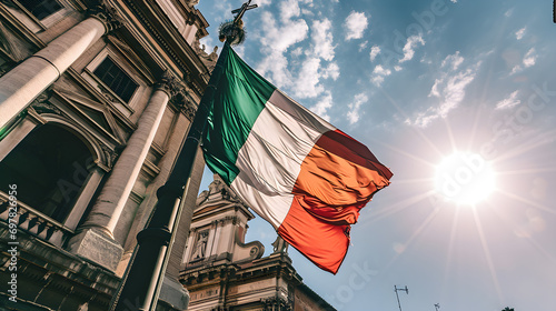 A stunning Italian tricolor national flag flutters in the wind on a pole with beautiful traditional Italian buildings in the background.	 photo