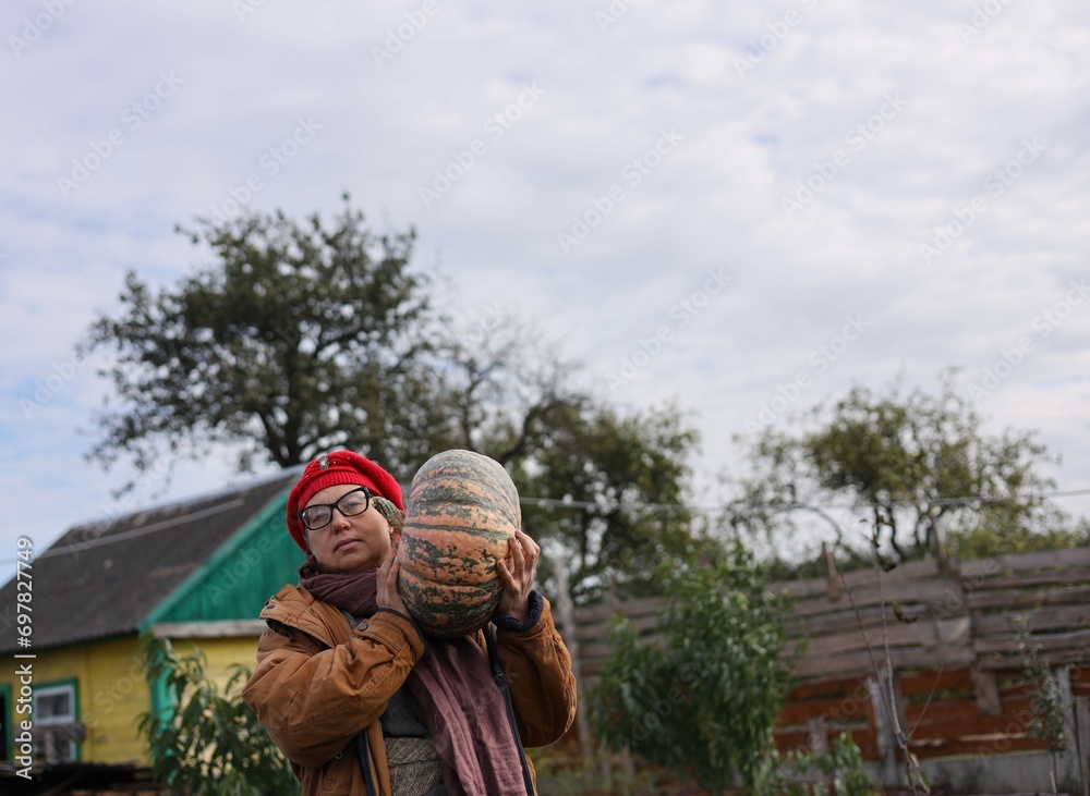 Middle aged woman in garden with pumpkin