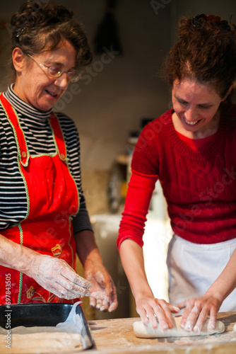 Senior Woman Guiding a Young Apprentice in the Process of Handmaking Bread Dough photo