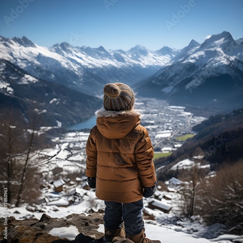 Fényképezés Niño en la cúspide de una montaña mirando el paisaje nevado en invierno
