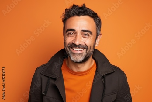 Portrait of a handsome man smiling and looking at camera against orange background