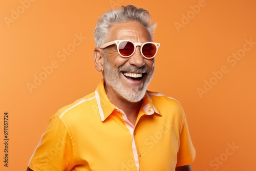 Portrait of happy senior man in sunglasses, isolated on orange background